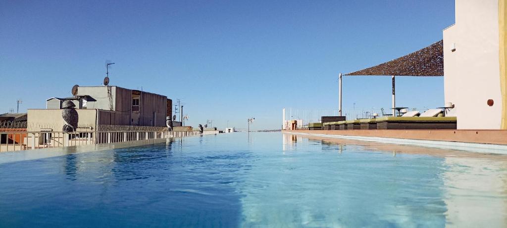 une piscine d'eau bleue à côté d'un bâtiment dans l'établissement Hotel Orangine, à L'Hospitalet de Llobregat