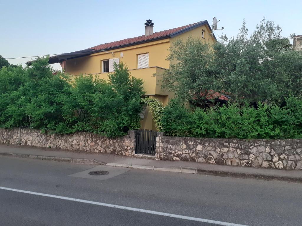 a yellow house sitting on the side of a road at Apartmani Ljerka Malinska in Malinska