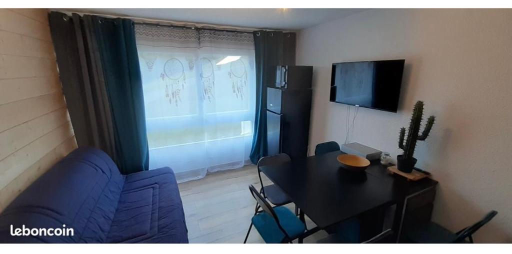 een woonkamer met een tafel en een blauwe bank bij Studio Puy saint vincent 1600 in Les Prés