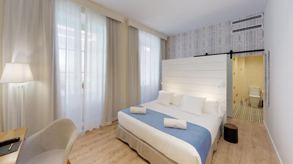 a bedroom with a bed and a desk and a chair at Madeinterranea Suites in Málaga