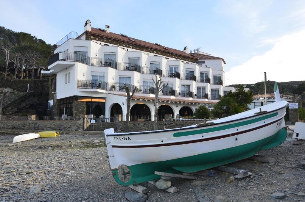 una barca seduta per terra di fronte a un edificio di Hotel Llane Petit a Cadaqués