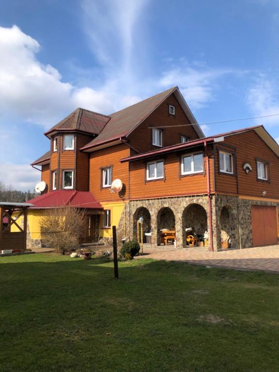 a large brown house with a large yard at Біля Погару in Slavske