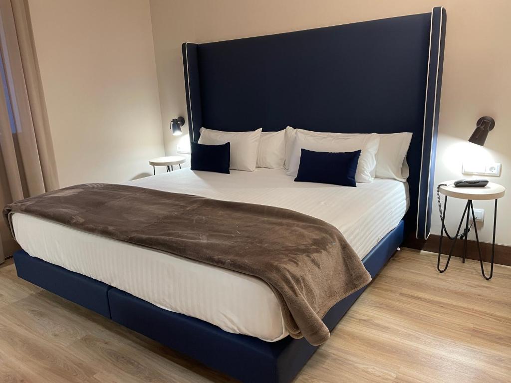 a bedroom with a large bed with a blue headboard at Hotel Maria Cristina in Toledo