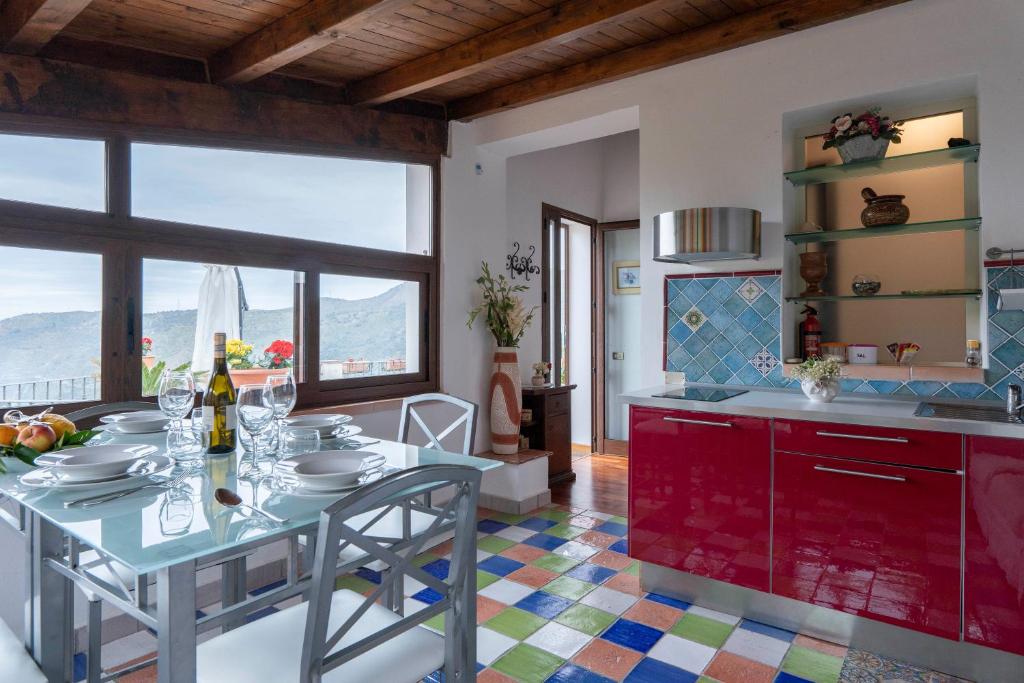 una cucina con tavolo da pranzo e una cucina con armadi rossi di La Finestra sulle Eolie a Reitano