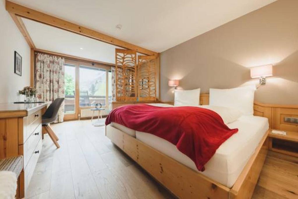 a bedroom with a large bed with a red blanket on it at Alpenhotel Montafon & SPA in Schruns