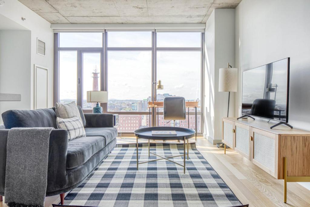 a living room with a couch and a large window at Luxury Fort Point 1BR w WD Gym BOS-488 in Boston