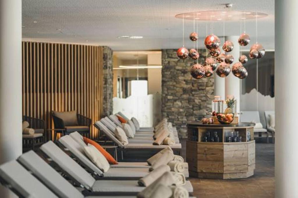a room with a bunch of couches and a chandelier at Alpenhotel Montafon & SPA in Schruns