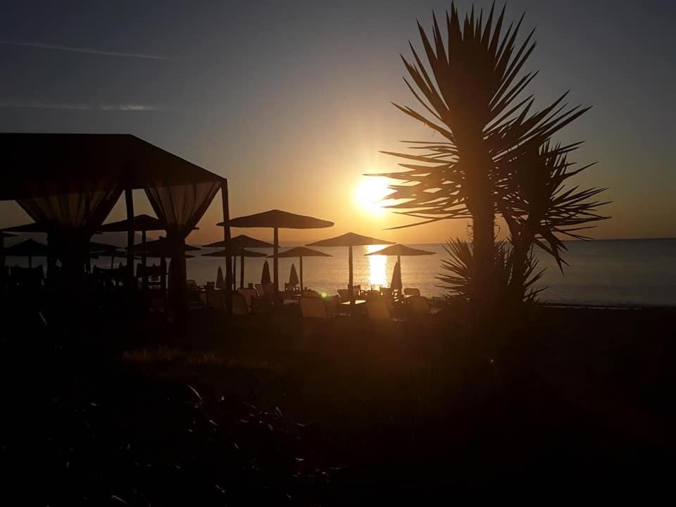 a sunset on a beach with umbrellas and a palm tree at Villa Le Chocolate in Vrasná