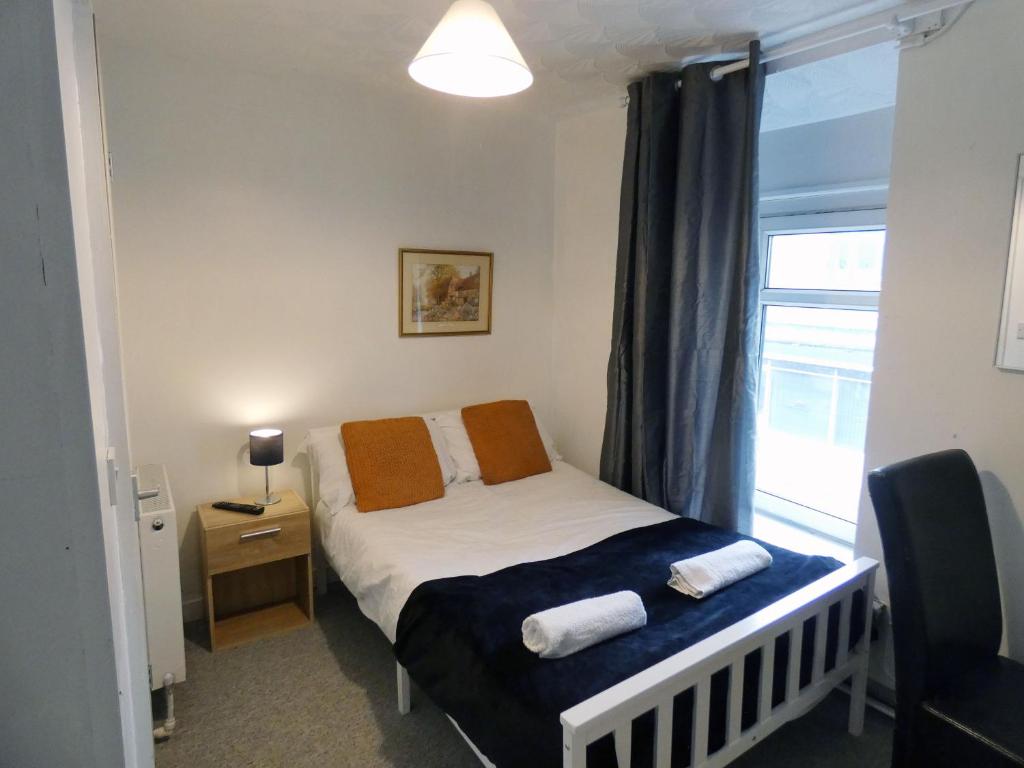 a small bedroom with a bed and a window at Bridge Street En Suite Rooms in Merthyr Tydfil