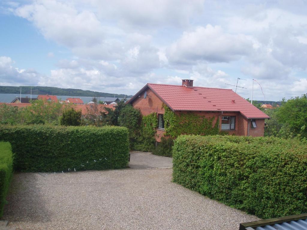 uma casa com um telhado vermelho e alguns arbustos em Glyngøre Bed & Breakfast II em Glyngøre
