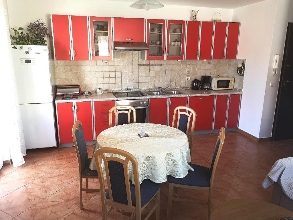 Apartment Vjera Ližnjan في ليجيان: مطبخ مع دواليب حمراء وطاولة مع كراسي