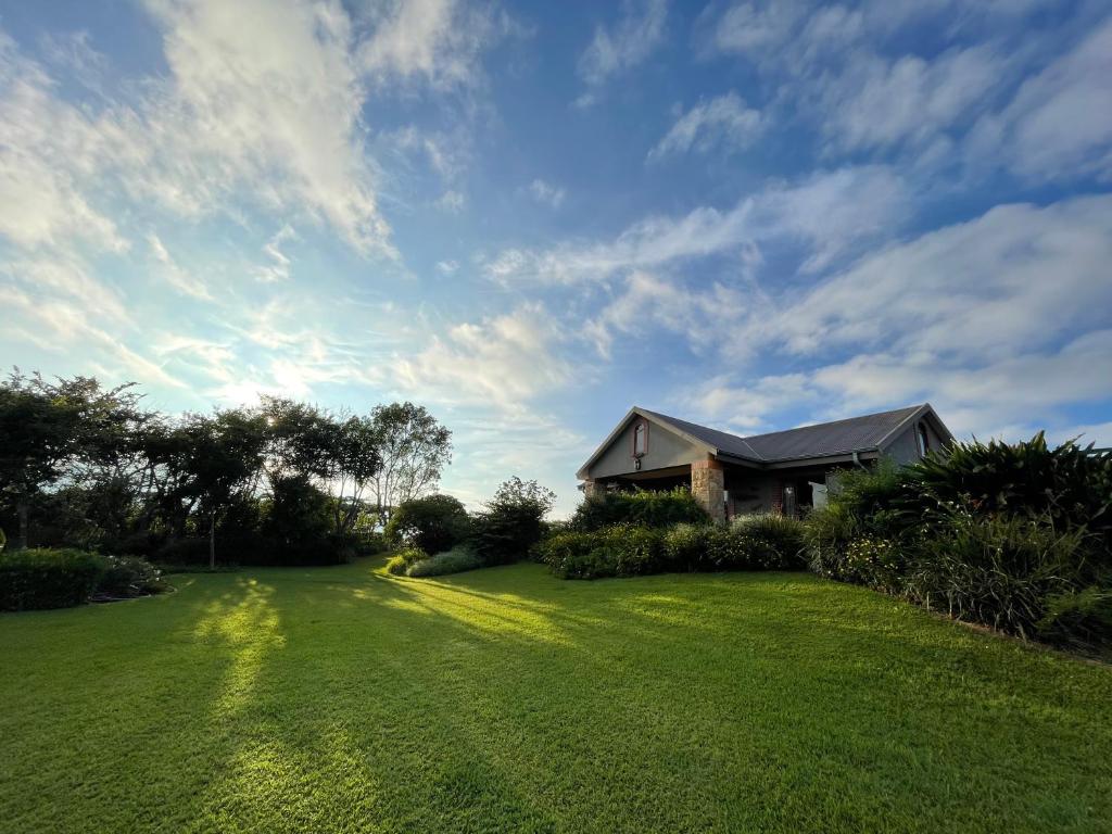 een huis met een grote tuin met een groen gazon bij Ha'Penny Hill in Tzaneen