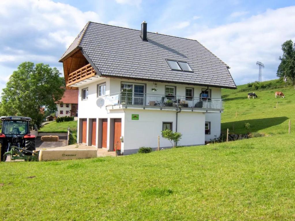 ein Haus auf einem Hügel mit einem Traktor davor in der Unterkunft Haus Mühlenfranzenhof in Schönwald