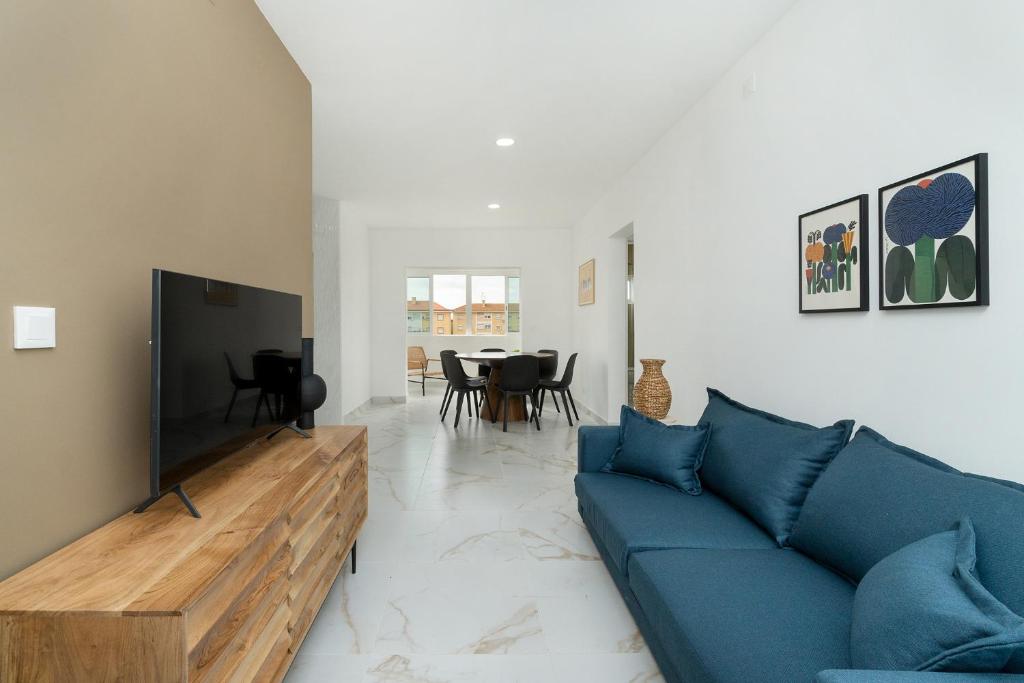 sala de estar con sofá azul y TV en Estrela Do Mar Apartment by Olala Homes en Cascais