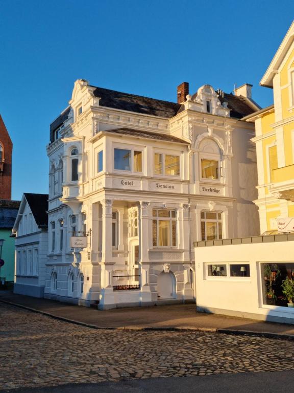 ein großes weißes Gebäude an der Straßenseite in der Unterkunft Hotel Beckröge in Cuxhaven