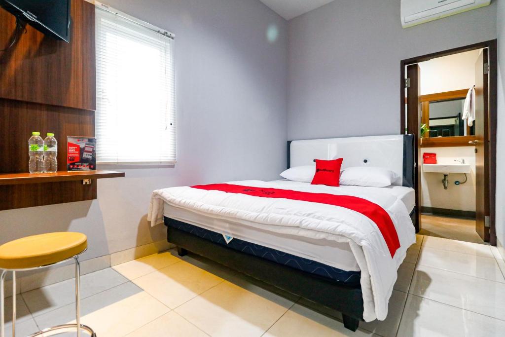 um quarto com uma cama grande e um cobertor vermelho em RedDoorz near Kebon Jeruk Jakarta em Jakarta