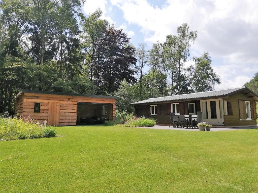 ein Blockhaus mit einem großen Garten davor in der Unterkunft Bungalow aan de Visbeekvallei in Vlimmeren