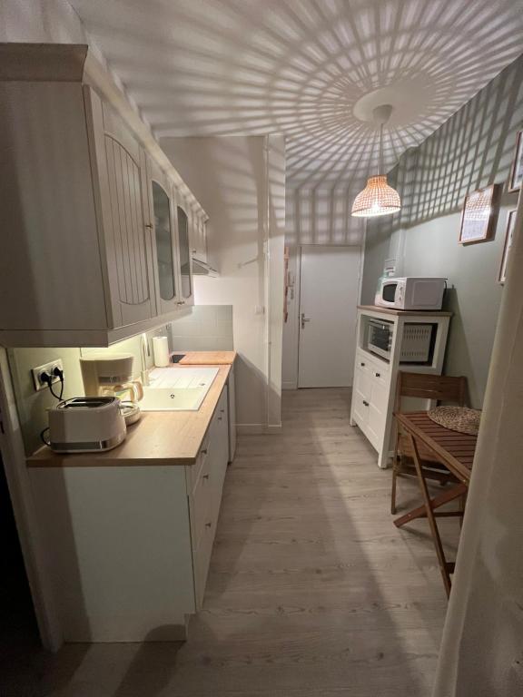 una cucina con armadi bianchi e soffitto di Studio «  La Mouette Rieuse » a Le Touquet-Paris-Plage
