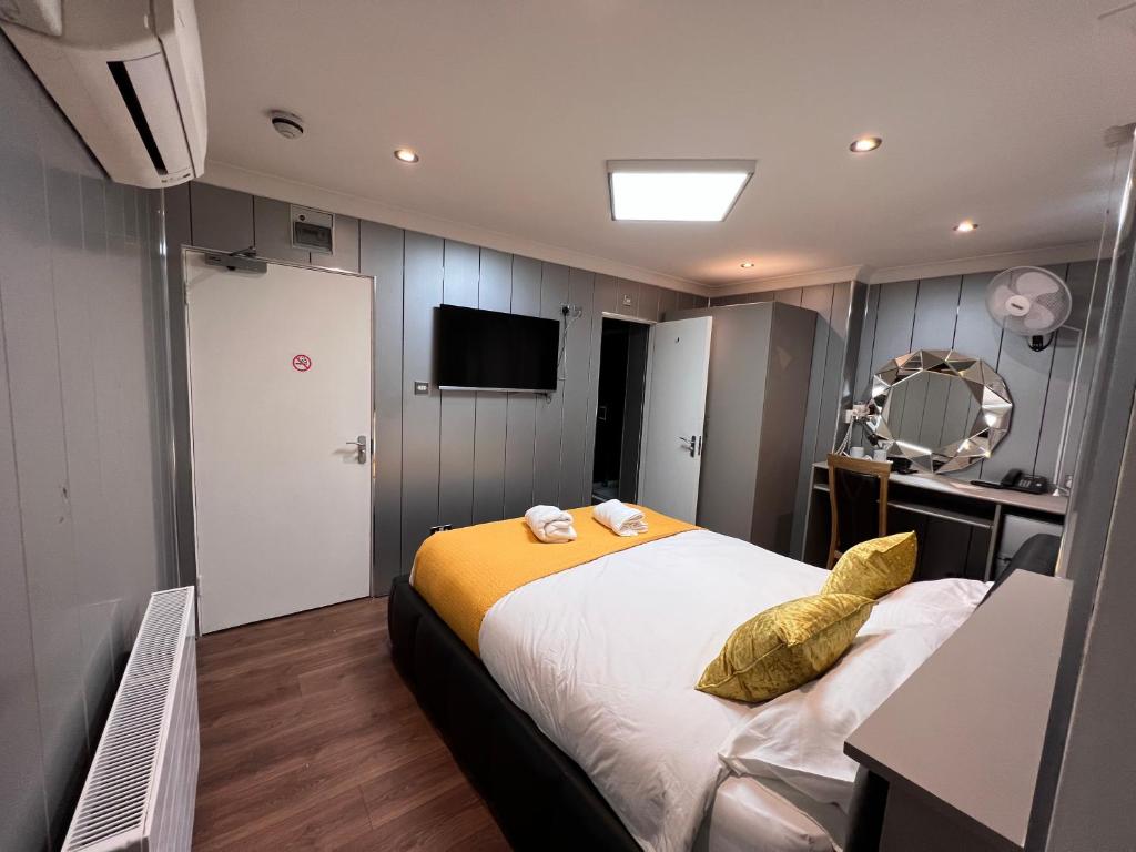 a bedroom with a large bed with yellow pillows at The Commongate Hotels in London