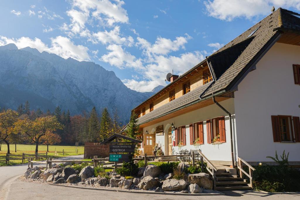 a white building with mountains in the background at Hiša Ojstrica in Solčava