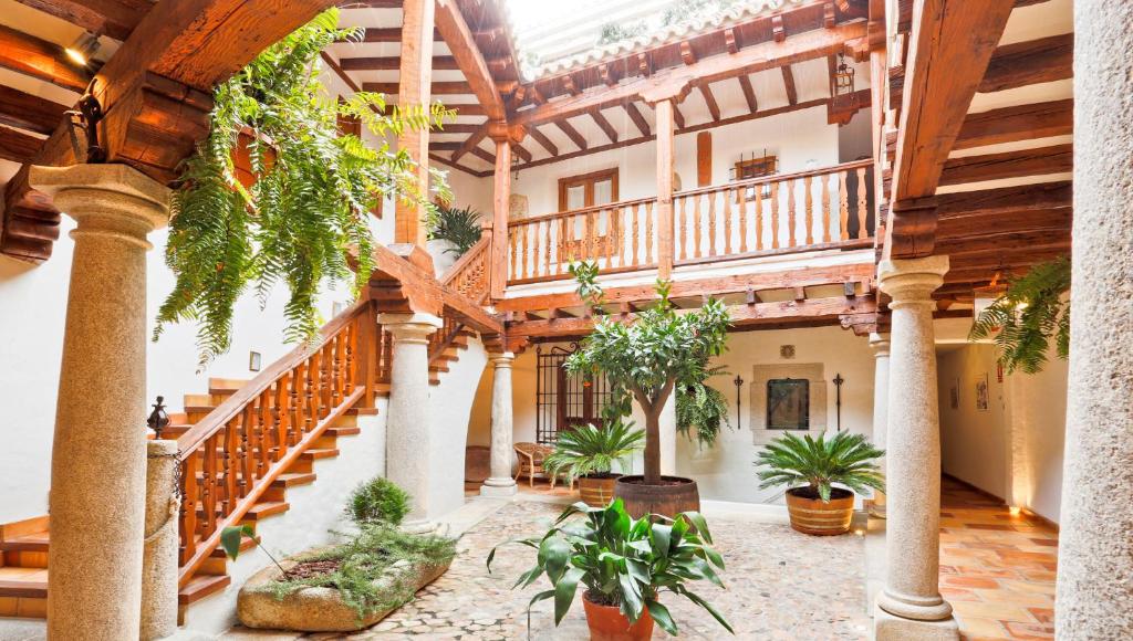 an indoor courtyard with a staircase and potted plants at Posada del Tio Juanón in Navalcarnero