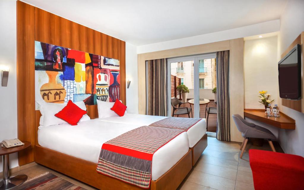 een hotelkamer met een bed, een bureau en een televisie bij Hotel Carlton in Tunis