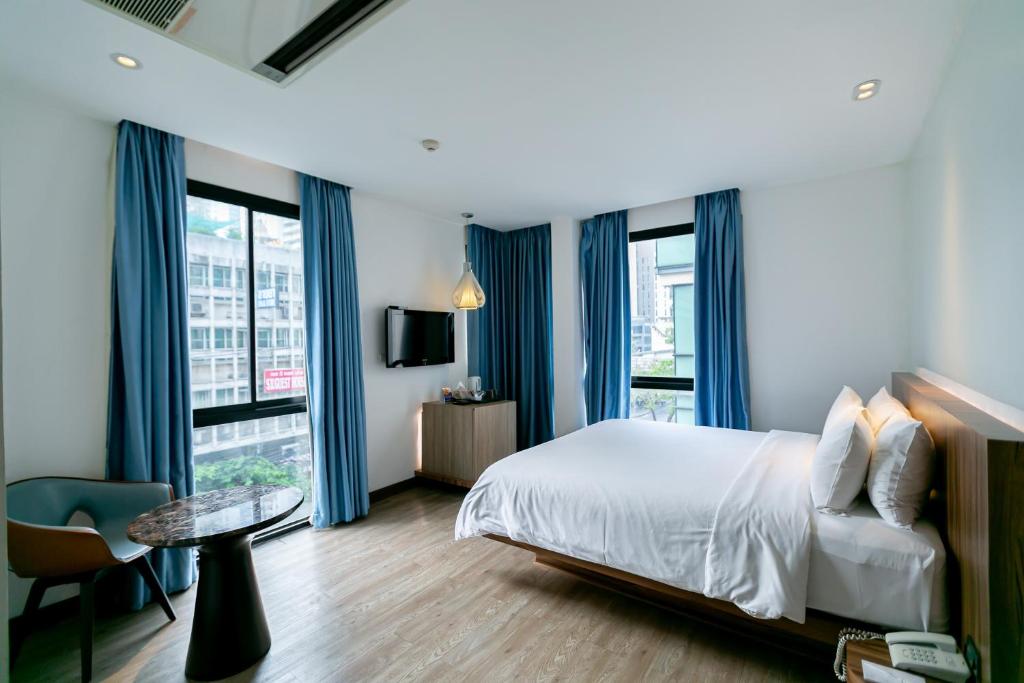 1 dormitorio con cortinas azules, 1 cama y 1 mesa en Uno Express (SHA), en Bangkok