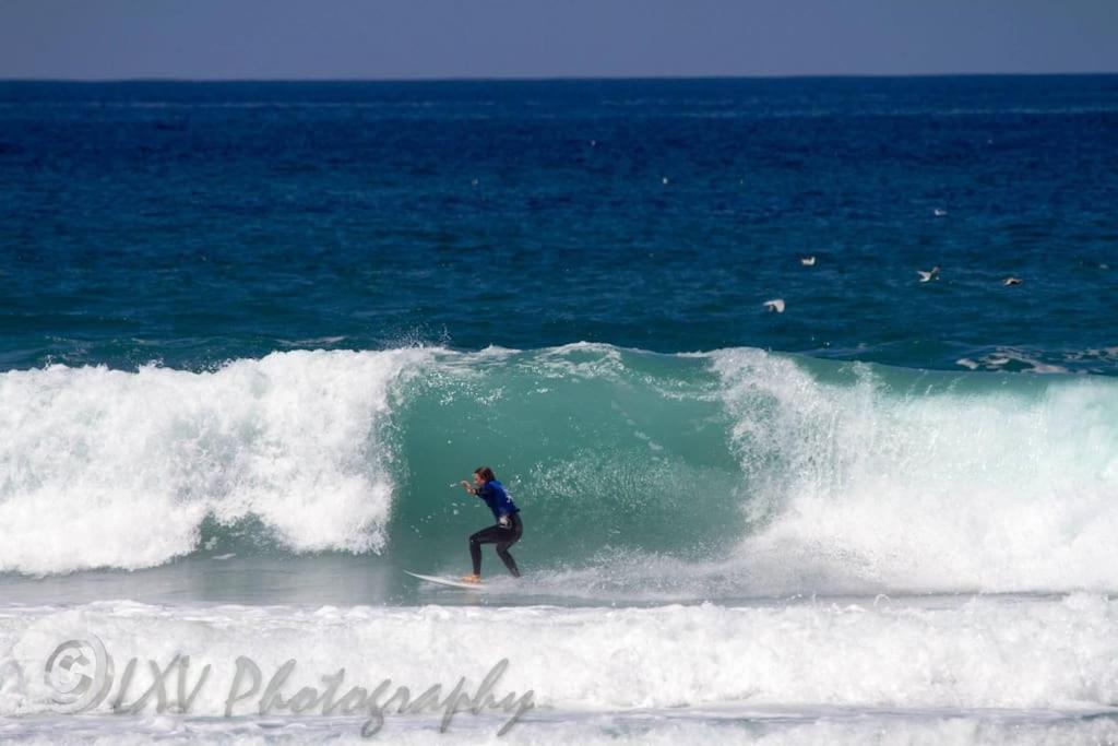 a person riding a wave on a surfboard in the ocean at Brook beach retreat, Porthtowan, Cornwall in Porthtowan