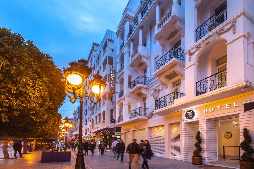 people walking down a street in front of a hotel at Hotel Carlton in Tunis