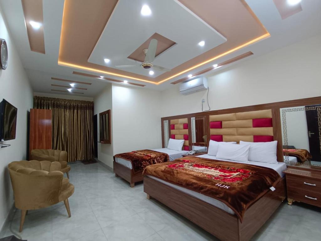um quarto de hotel com duas camas e uma cadeira em Hotel new royal palace em Lahore