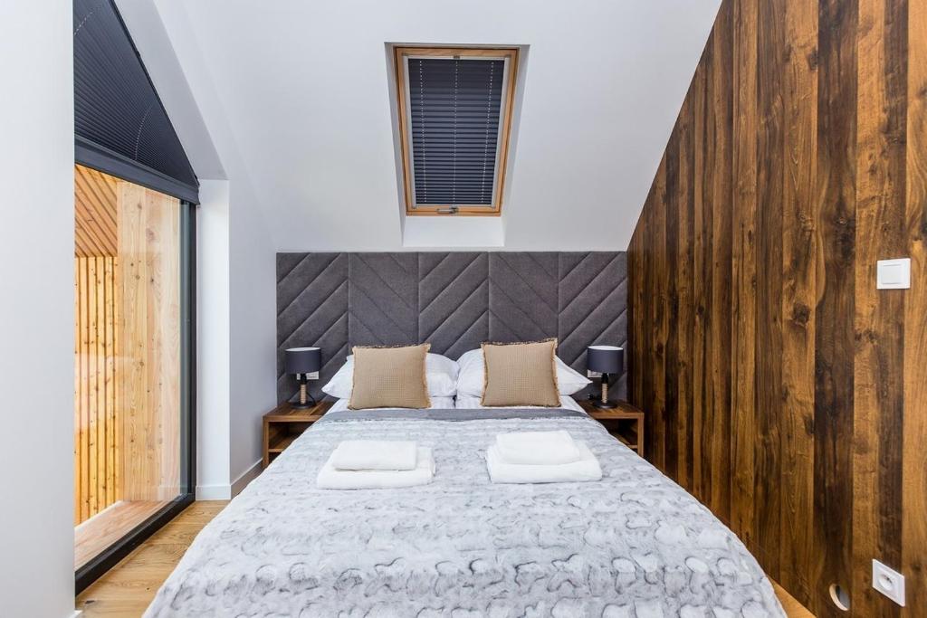 Compact bedroom with central bed, quilted grey headboard, skylight, sliding glass balcony door, warm wood paneling.