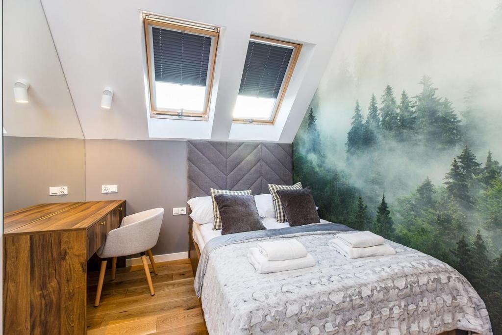 Cozy bedroom with skylight windows, upholstered headboard, folded towels on bed and forest mural.