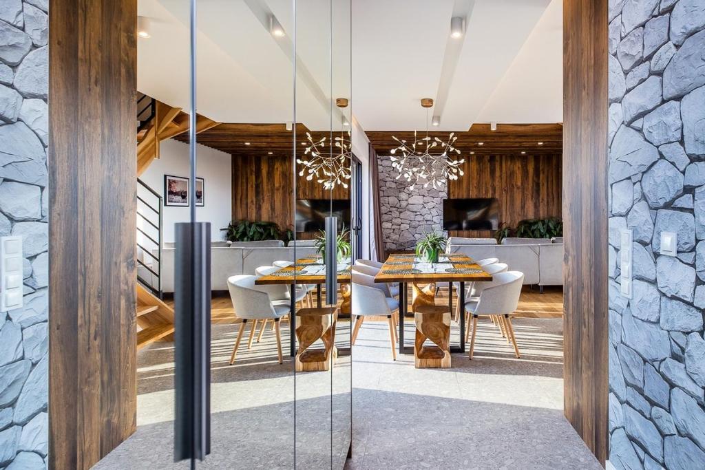 Entrance framed by mirrored doors opening onto dining area with wooden table and decorative chandelier.