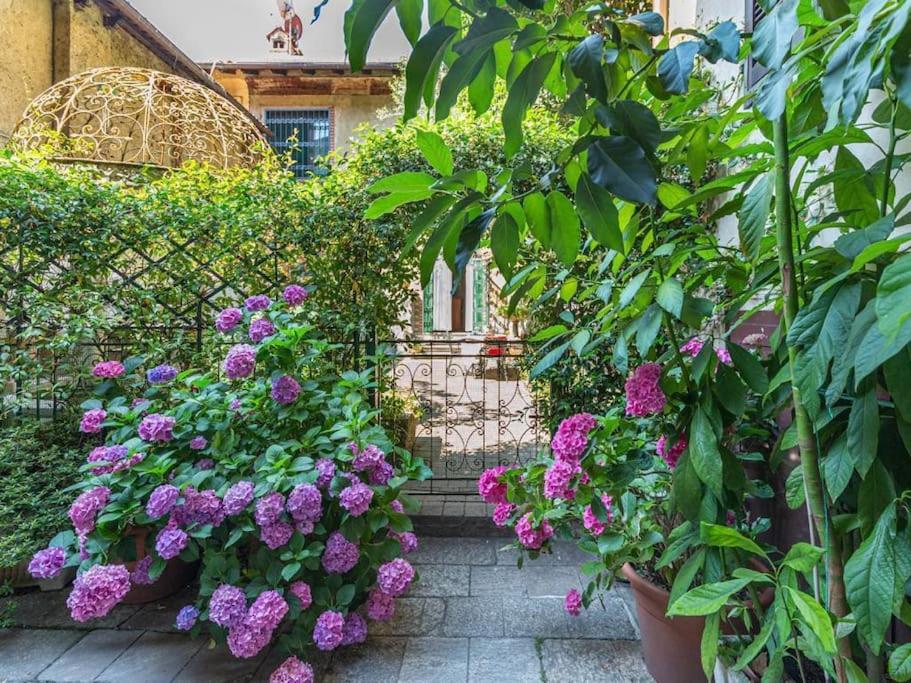 un jardín con flores púrpuras y una valla en Villa Monastero, en Arona
