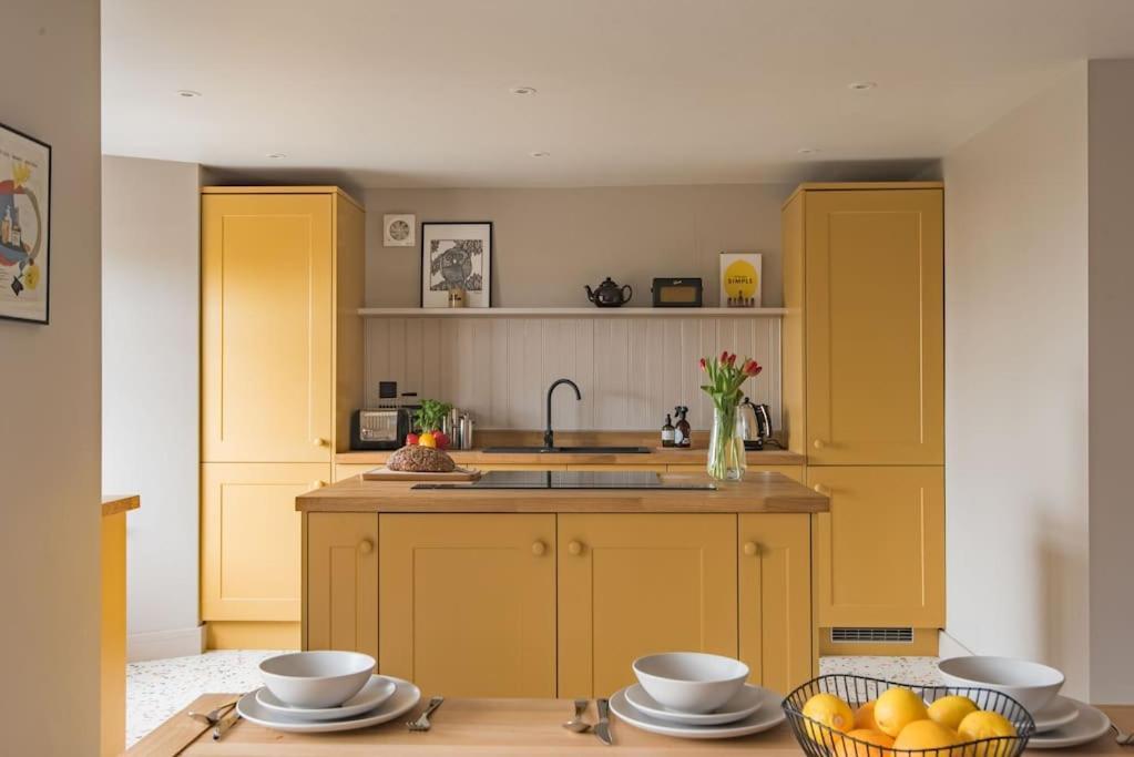 a kitchen with yellow cabinets and a sink and a table at Victory Cottage - Stunning home with sea views in Kingsdown