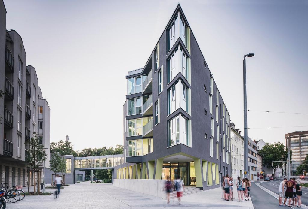 a tall black building with people standing on a street at Jugendherberge Braunschweig in Braunschweig