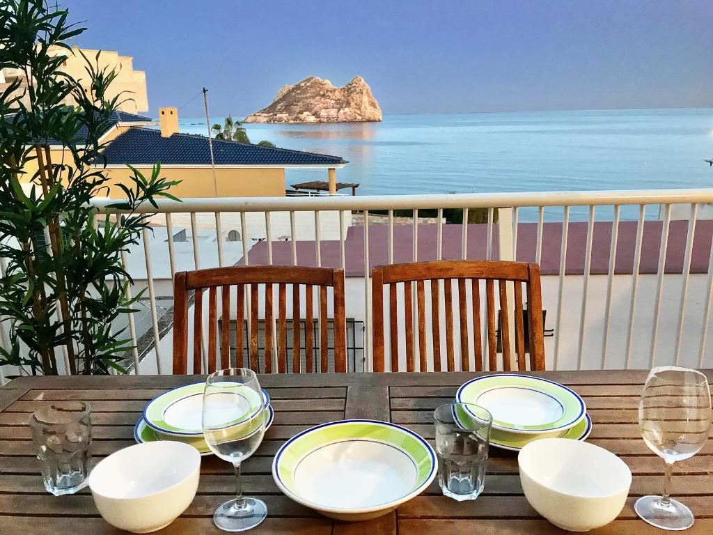 una mesa de madera con platos y copas de vino en el balcón en La Paloma, Chalet a pie de playa, en Águilas