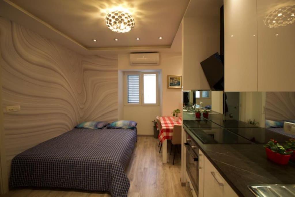 a small bedroom with a bed and a kitchen at Mitella studio apartman in Solin