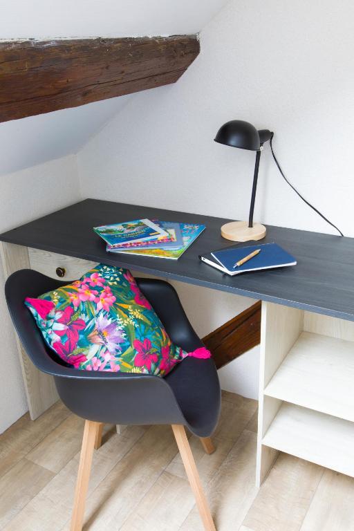 a black desk with a chair with a pillow on it at La couronne Maison 80m2 garage &amp; terrasse in Sainte-Croix-en-Plaine