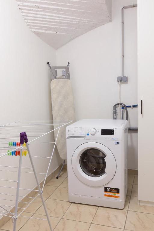 a washing machine in a room with a chair at La couronne Maison 80m2 garage &amp; terrasse in Sainte-Croix-en-Plaine