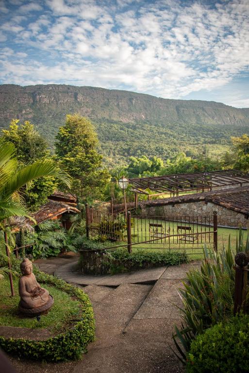 a statue of a buddha sitting on a path with a mountain at Brisa da Serra Pousada Boutique in Tiradentes