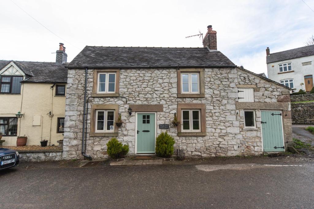 a stone house with green doors on a street at Dale End Cottage, Brassington in Brassington
