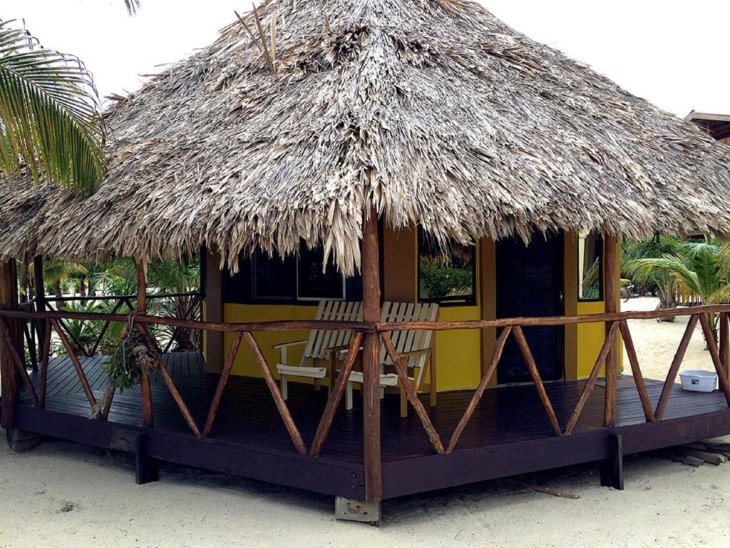 a hut with two chairs and a thatched roof at Heavens Gate Beach Bungalows in Placencia