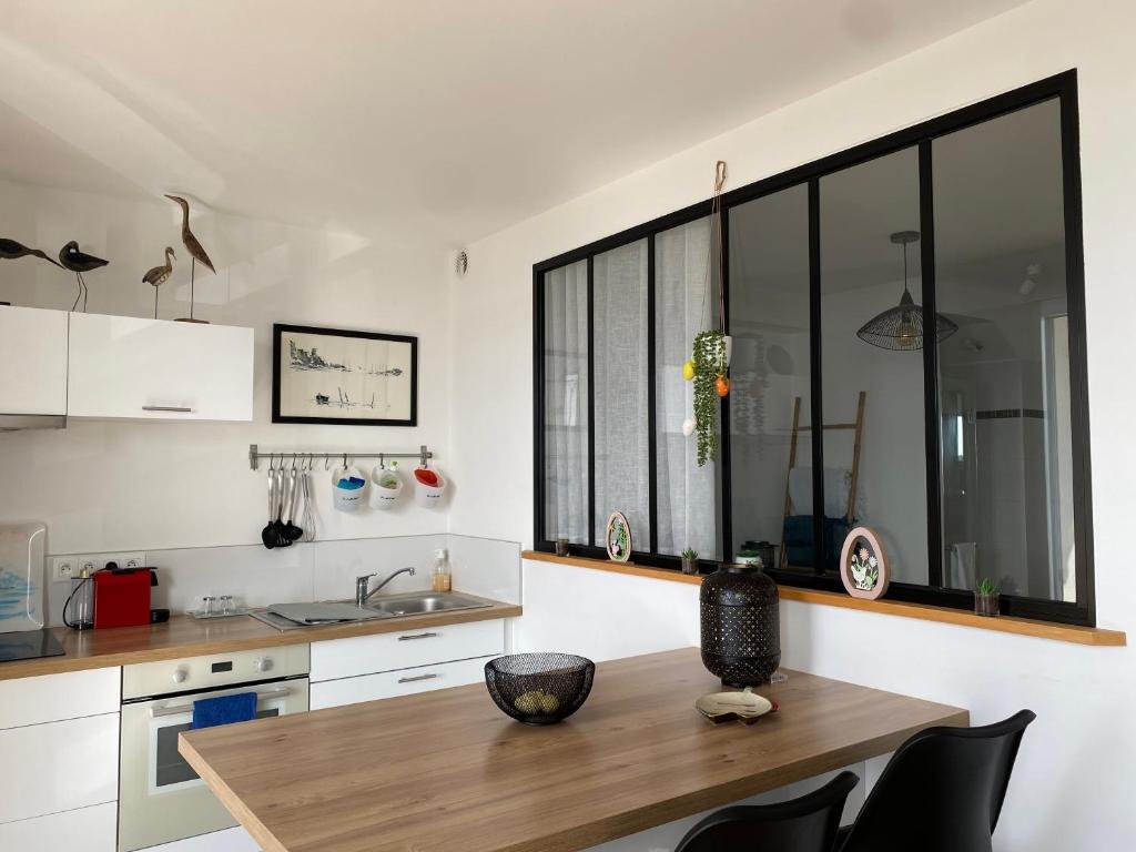 a kitchen with a wooden table and some windows at Splendide vue face à la mer avec garage in Concarneau