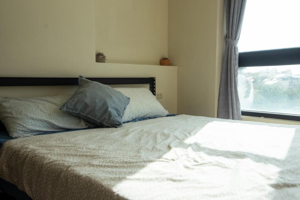 a bedroom with a bed with a pillow and a window at Bare Foot Diving Hostel 2 in Hengchun