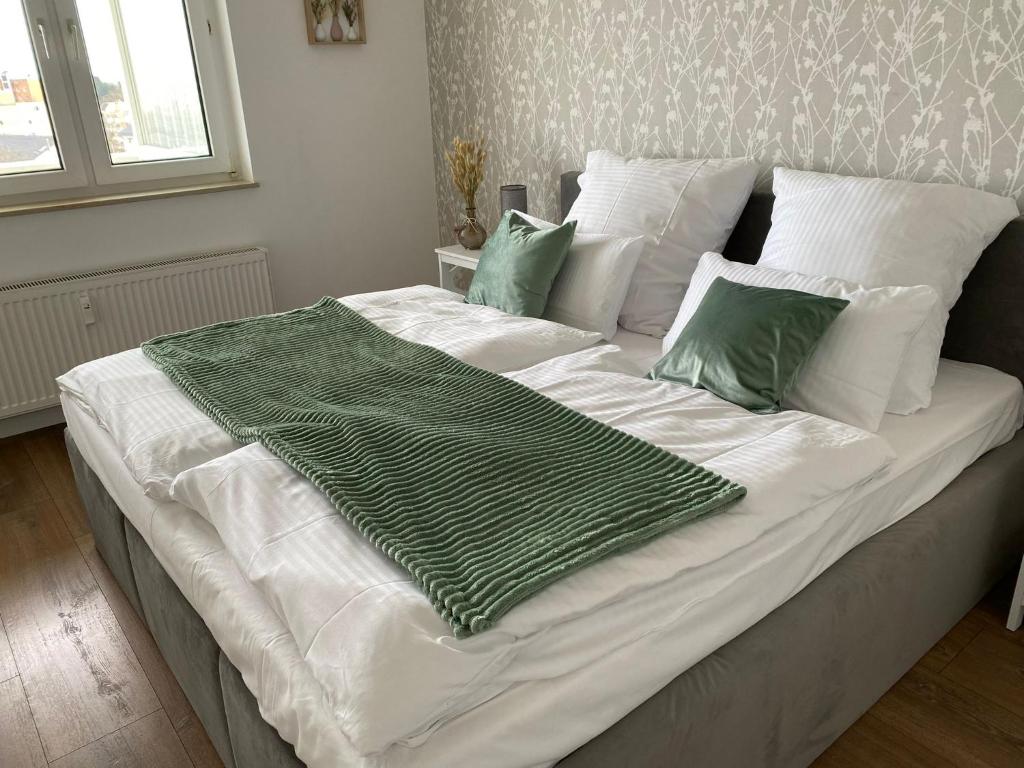 ein großes weißes Bett mit grüner Bettwäsche und Kissen in der Unterkunft SUITE4ME - Moderne Ferienwohnung I Küche I Balkon I Mainz-Kostheim in Wiesbaden