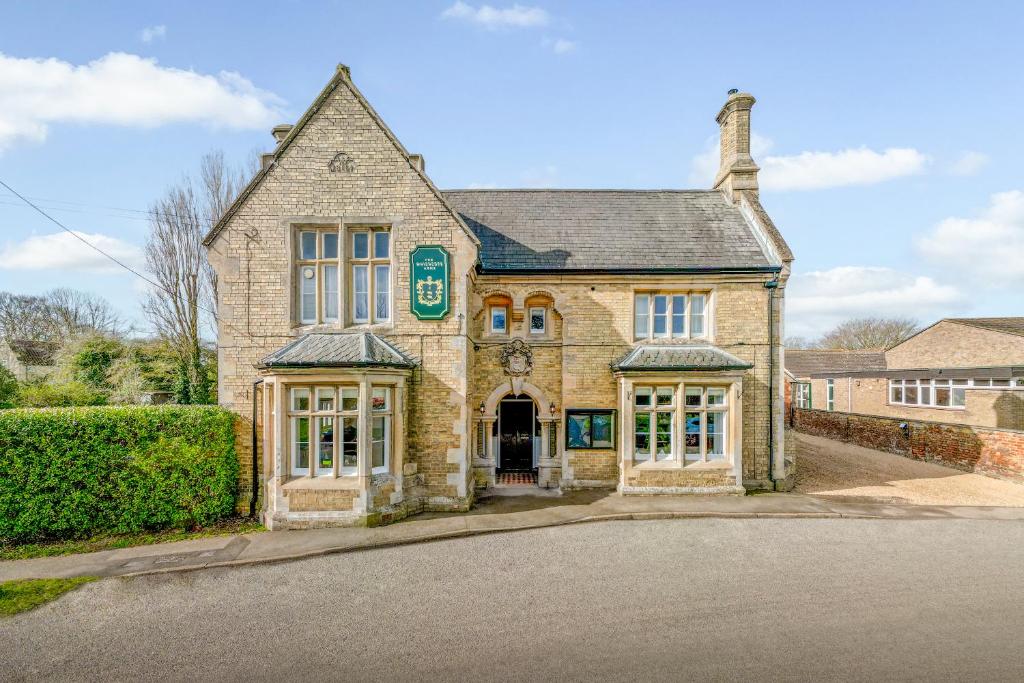 um velho edifício de tijolos com um sinal verde em The Whichcote Arms 