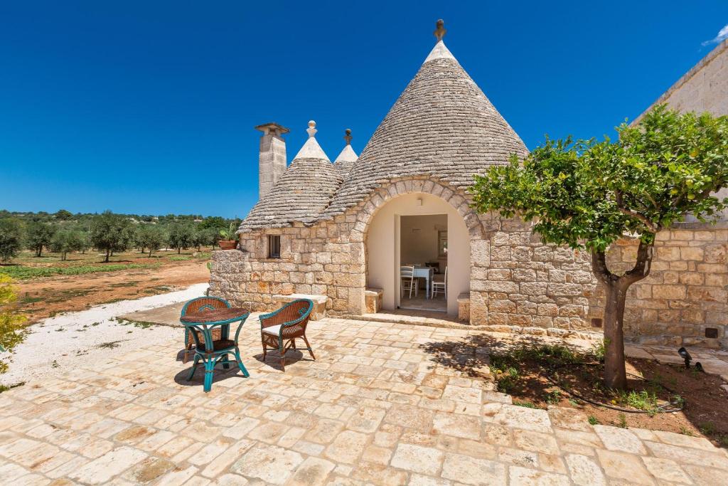 a stone building with a table and chairs on a patio at Masseria Macchia in Ceglie Messapica