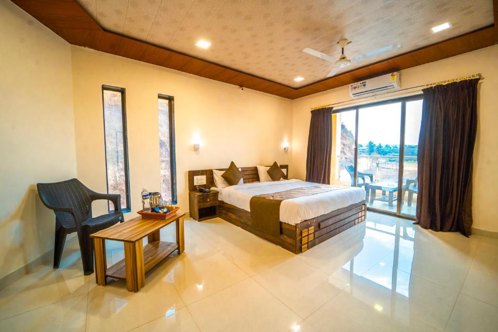 a bedroom with a bed and a table and a window at Vrindavan Resort in Mahabaleshwar