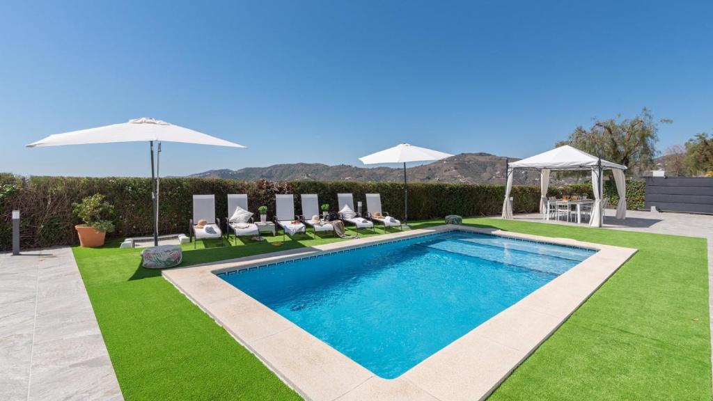 - une piscine dans une cour avec des chaises et des parasols dans l'établissement Cortijo Entre Pueblos Competa by Ruralidays, à Cómpeta